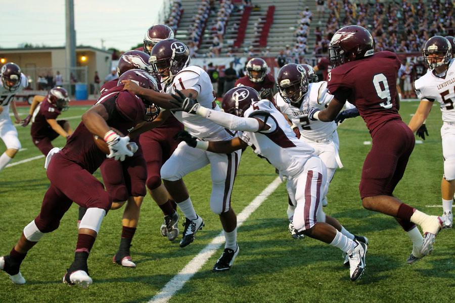 Rowlett player attempts to run the ball unsuccessfully as Lewisville Varsity players Kyle Naylor (number 31) and Xavier Franklin (number 5) block him, with Kenny Phillips (number 2) coming up fast.