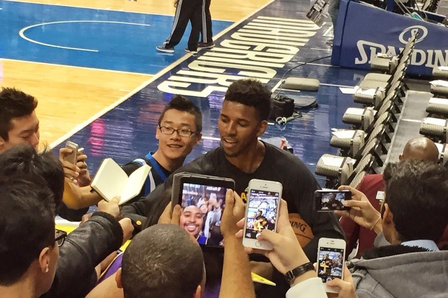 Los Angeles Lakers basketball player Nick Young, aka Swaggy P,  signs a poster while Jackie Guerrero is in front trying to get a signature with him. 