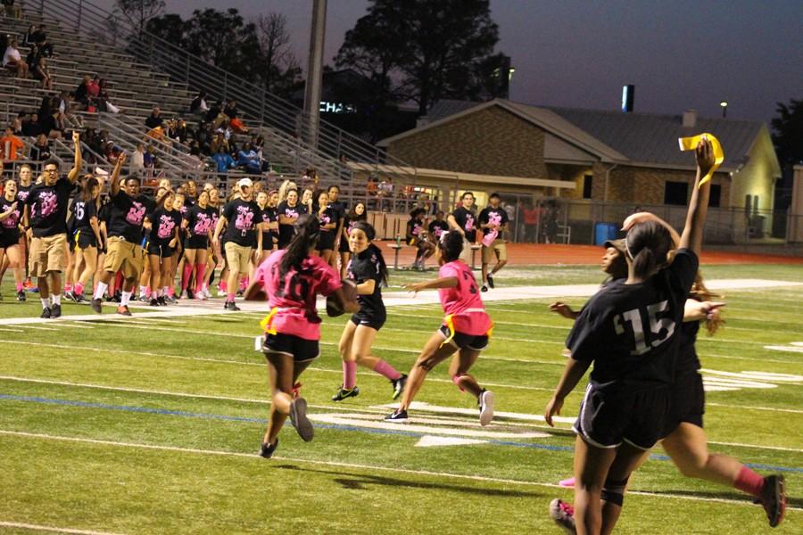Seniors tackle by stealing the flag of the ball holding juniors, as Senior girl coaches cheer, at the April 20 Powderpuff game.