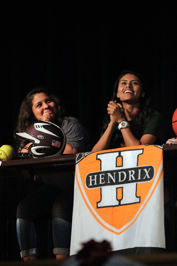 Softball players Summer Quiroga (left) and Gaby Vasquez (right) laugh and smile as they wait to sign their future college careers.
