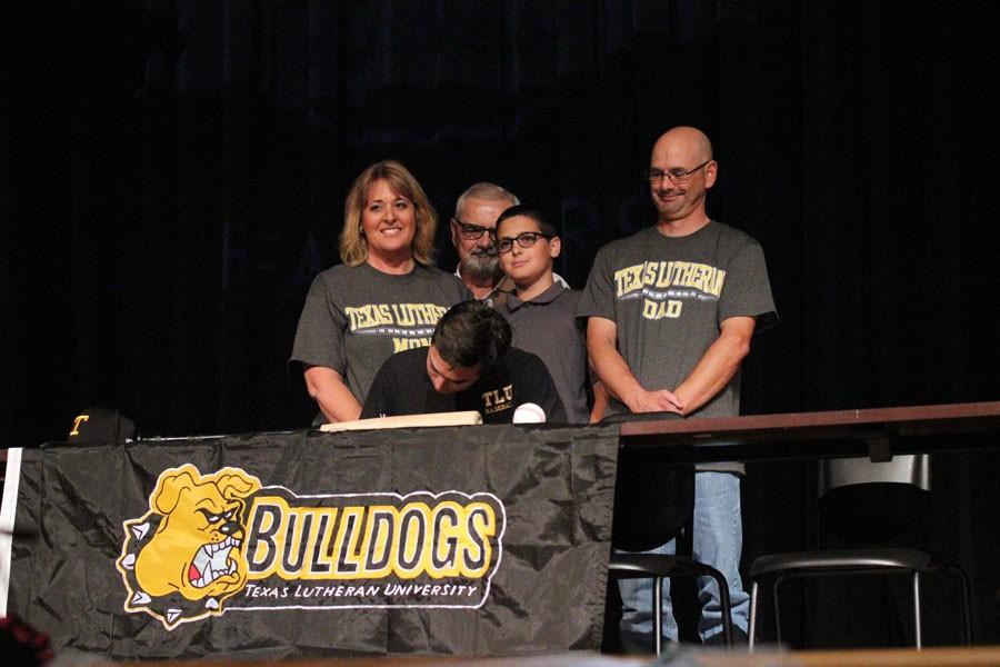 Pitcher Cody Rimko signs to Texas Lutheran as his family stands behind him looking on. 