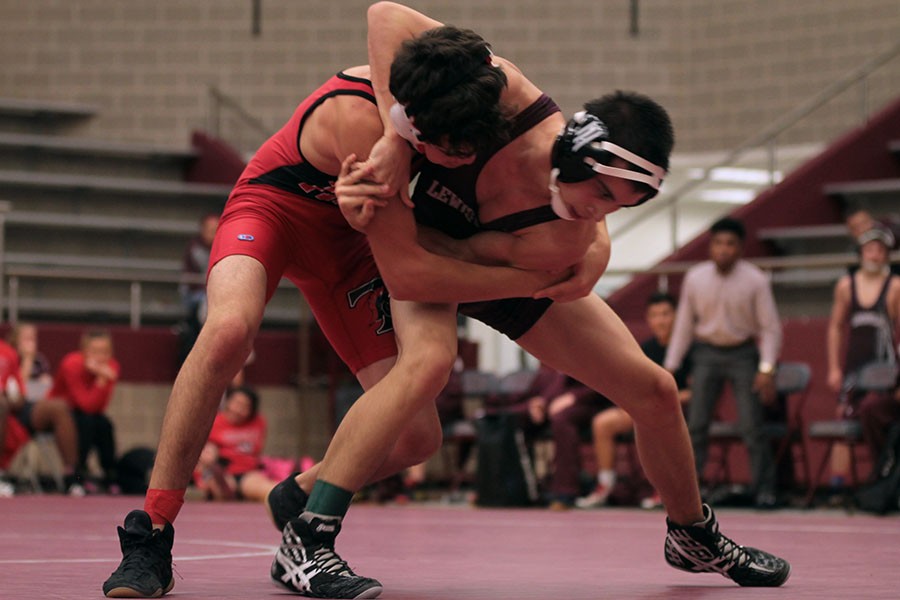 Junior Jordan Forscha attempts to take down his opponent by throwing him in a headlock in the Trinity Meet. 