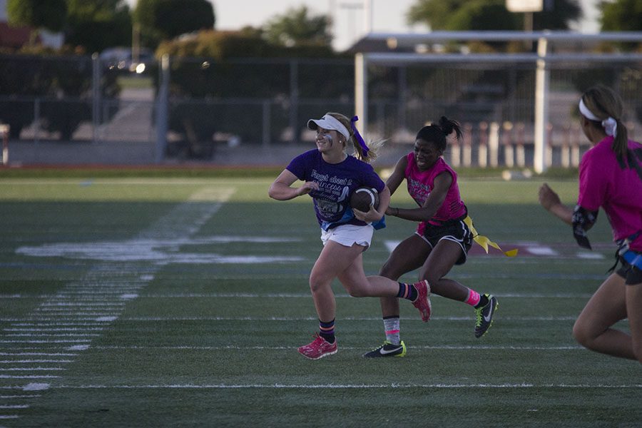 Senior Nicole Nelson attempts to run up the field as junior player Sharmaine Harper pulls at her flags. 