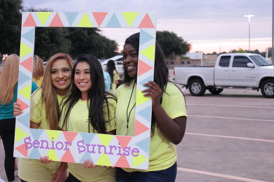 Seniors Sarah Cabrera, Myranda Olivia and Lovelyn Okoro pose for a picture with the sunrise behind them.