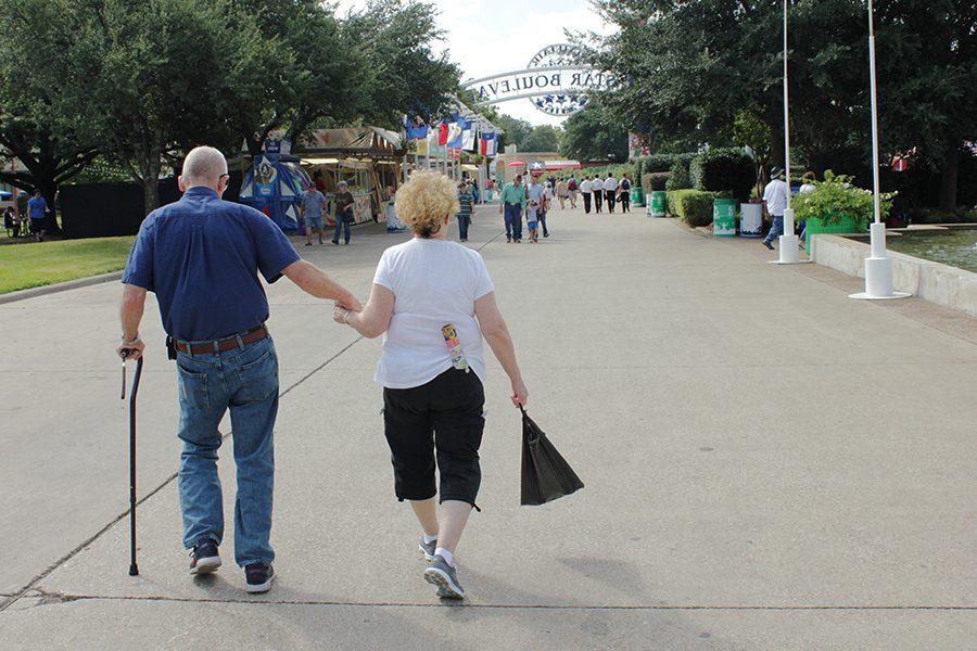 An elderly couple holds hands as they stroll through the State Fair of Texas.