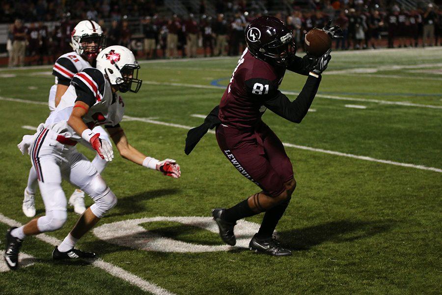 Senior Dwight Walker (81) struggles to keep the ball in his hands while Marcus High School players close up during the game on Friday, Sept. 30.