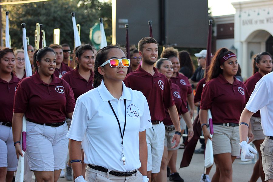 The color guard follows the lead of Junior Drum Major Allison Oropeza during Lewisvilles Homecoming Parade.  