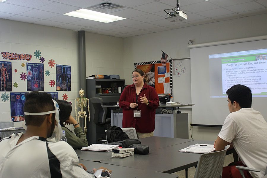 Lisa Powers teaches a pharmacy technician class as her students listen.