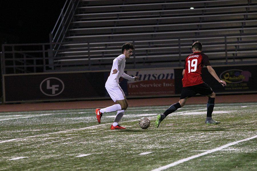 Senior Carlos Galvan (13) attempts to dribble past his opponent.