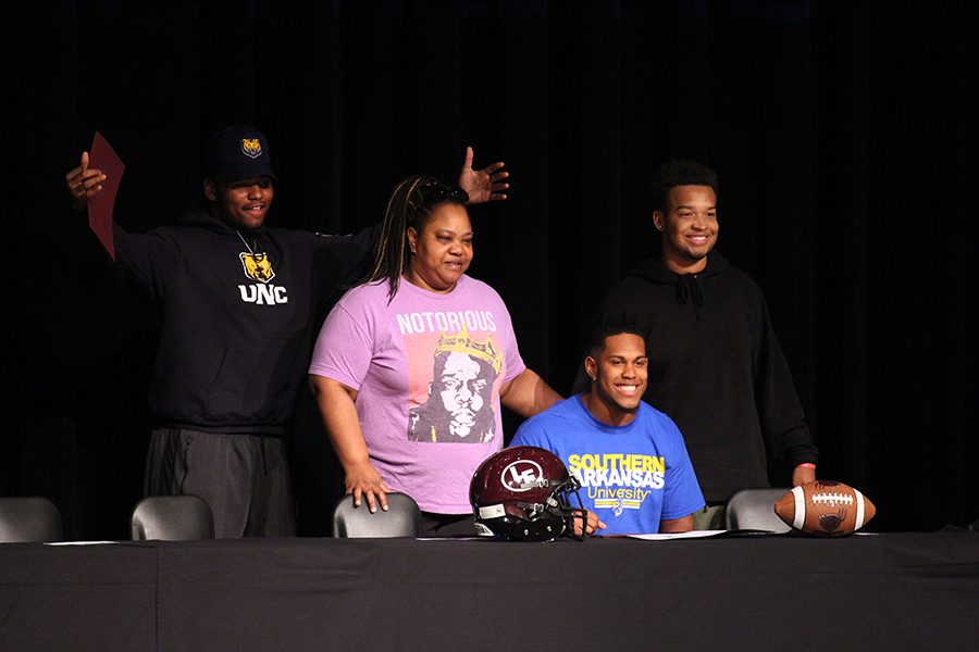 Ahmadric Pelican poses as he signs to Southern Arkansas University for football with his mom and friends by his side.
