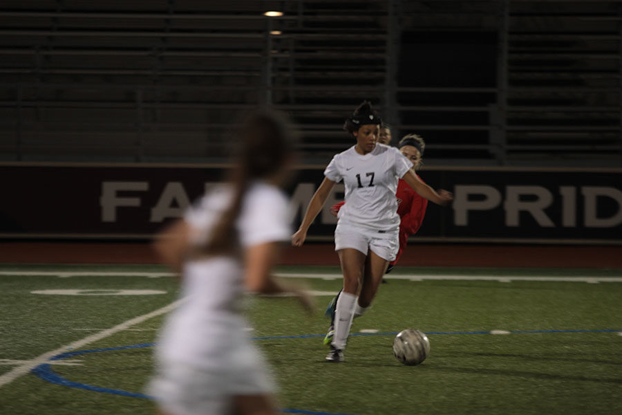 Senior Alexis McKinney (17) dribbles the ball as she prepares to pass to a teammate.
