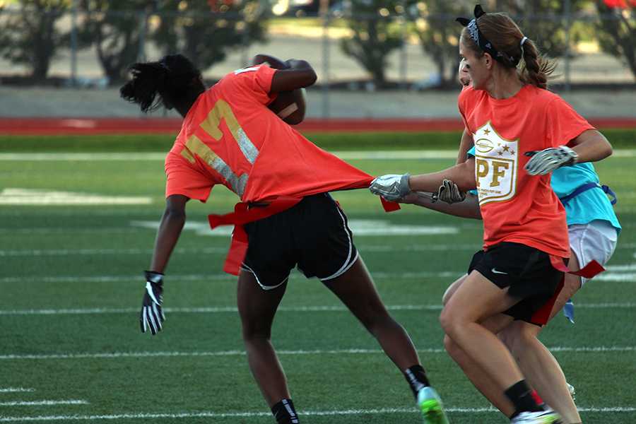 Senior Hannah Curtis attempts to pull the opponents arm away as they pull on senior Sharmaine Harpers flags.