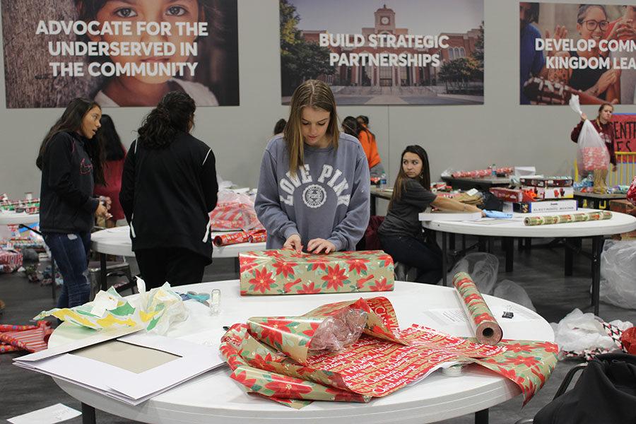 Senior, Maya Maldonado (center), taping a present. Senior,Gabby Tapia (on the right), looking back to the other helpers.