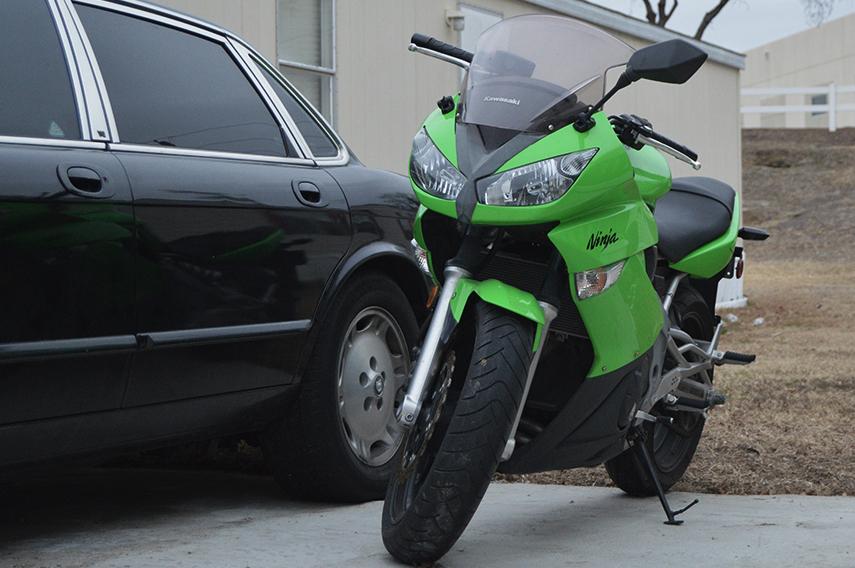 A bright green Kawasaki Ninja motorcycle sits in a driveway.
