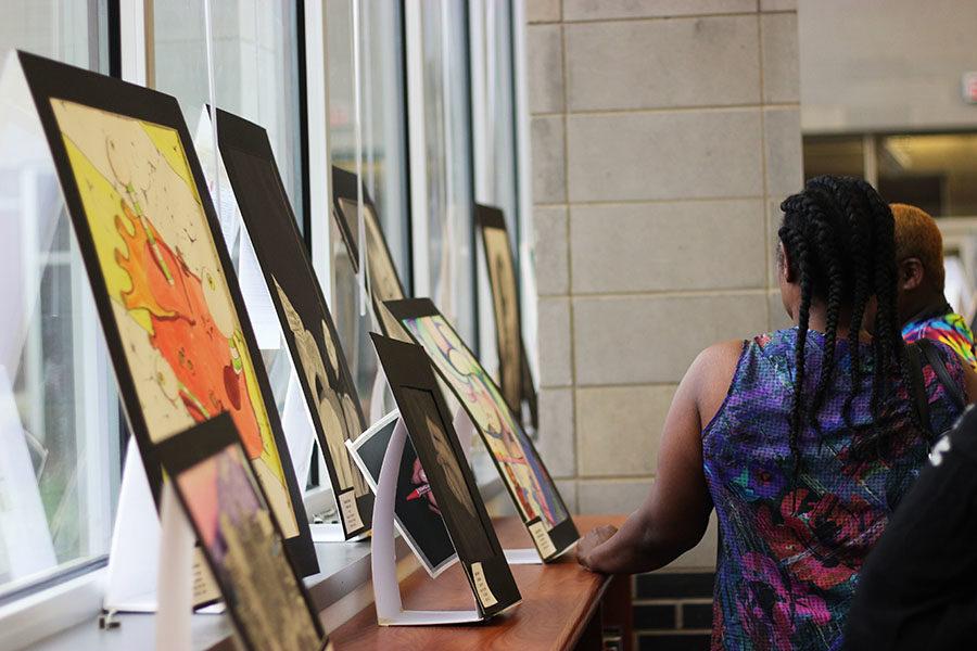A student looks at the artwork being displayed.