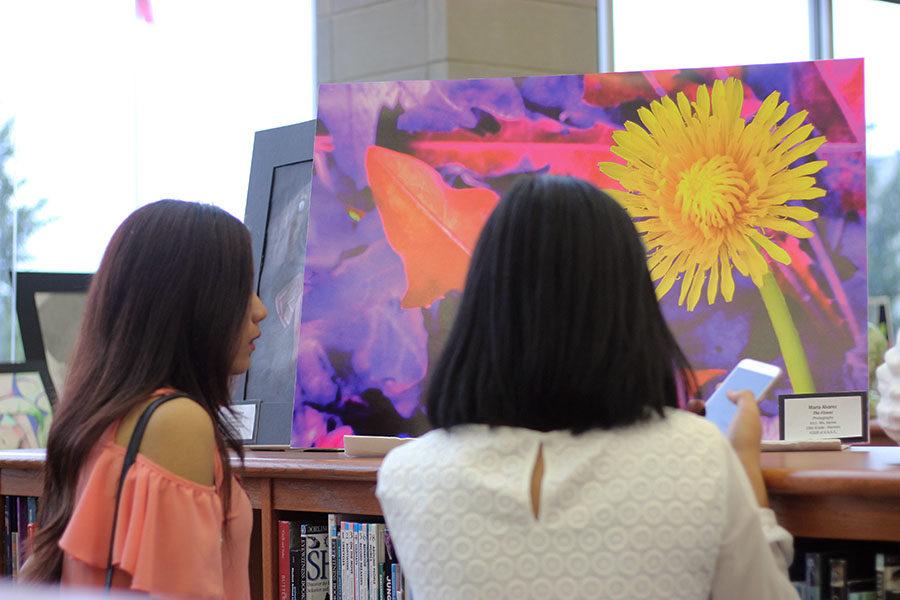 A student and parent glance at sophomore Maria Alvarezs The Flower.