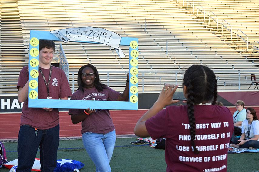 Seniors Nathan Toldan and Constance Smith pose in the frame while another student takes their photo.