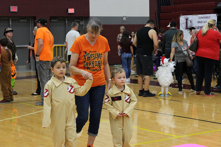 Two children dressed up as characters from the movie Ghostbusters walk through the gym.