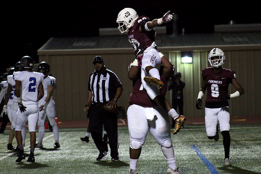 Senior Kwentin Huddleston (74) lifts senior Josh Lockhart (20) into the air to celebrate a touchdown at the home game against Hebron on Friday, Nov. 2. This touchdown put the overall score at 27-14.