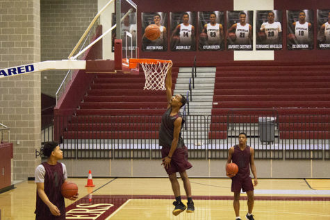 Senior Jason Lilly (24) hangs from the rim while dunking a ball during fourth period basketball practice on Tuesday, Jan. 29. 
