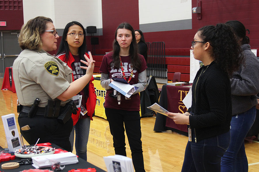 A sheriff talks to a group of students about their program during the college and career fair.