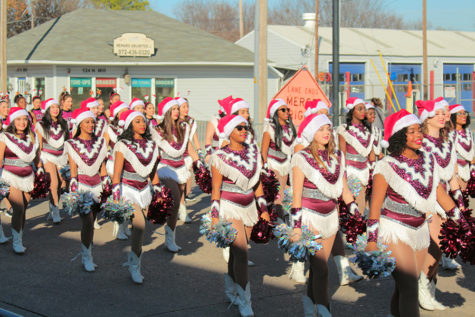 The Farmerettes walk in sync behind the band during the parade with santa hats on.