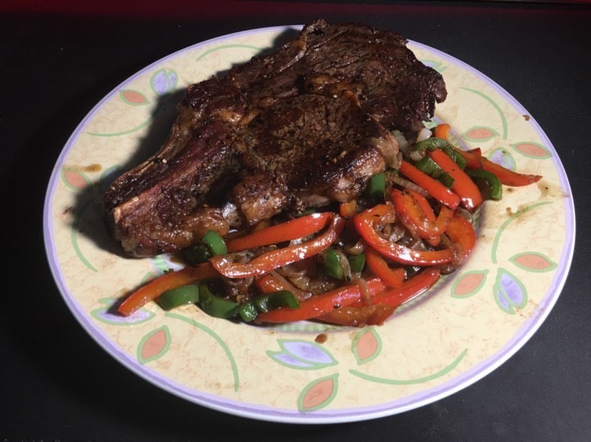 A ribeye steak with sautéd onions and peppers is prepared by senior Erick Nguyen.