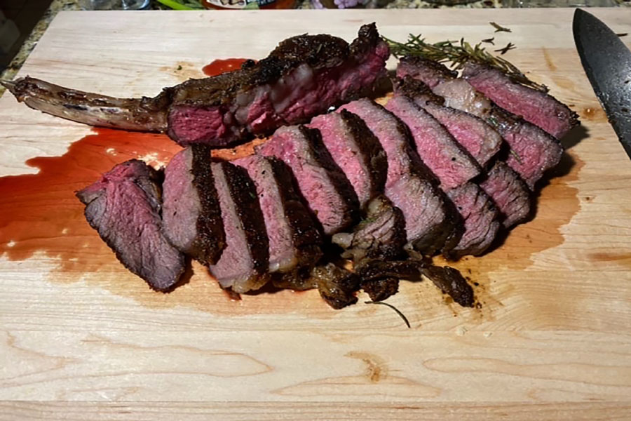 Tomahawk ribeye cooked to medium rare and cut evenly by senior Erick Nguyen rests on a cutting board.