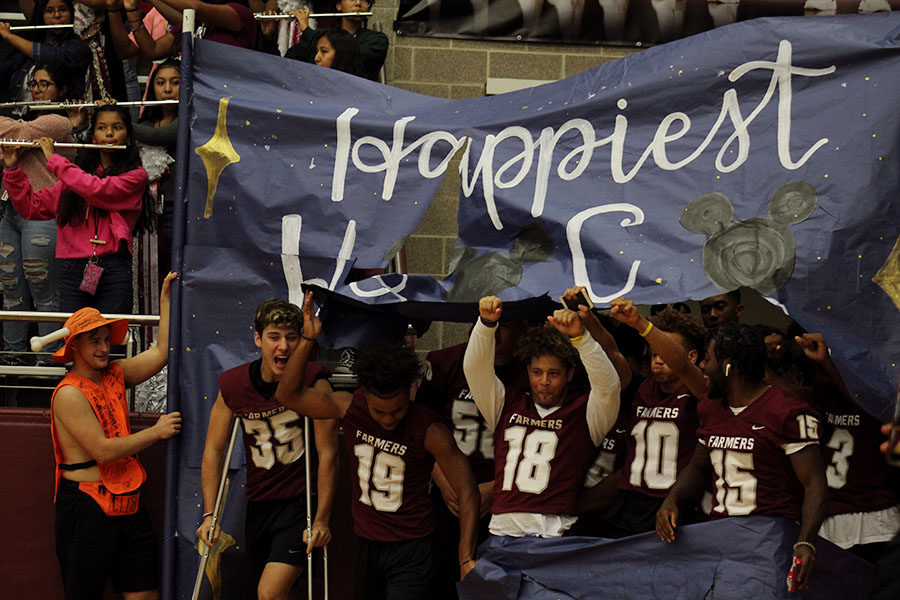 The Fighting Farmer football team breaks through a banner made by StuCo to kick off the homecoming pep rally on Friday, Oct. 4.