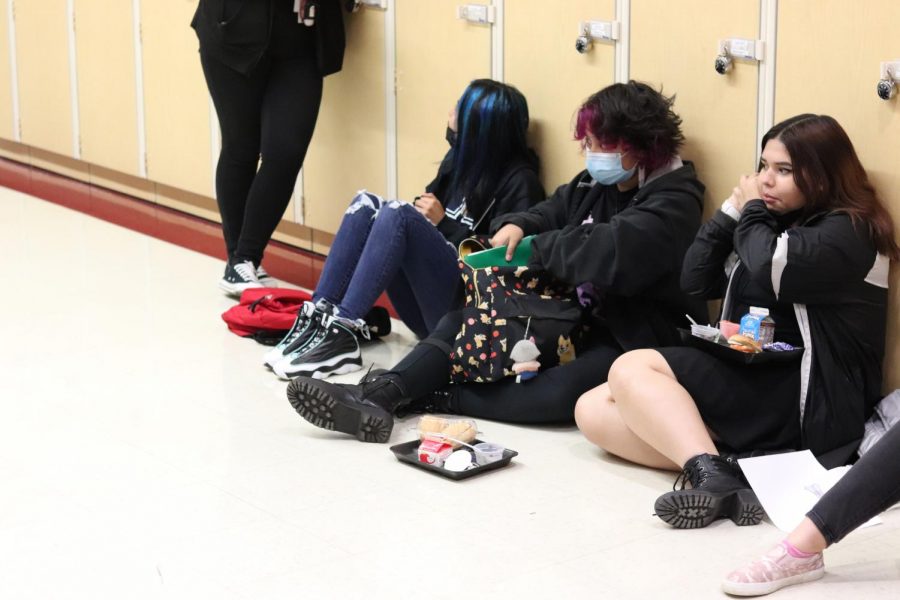 Students eat lunch on the floor against the lockers