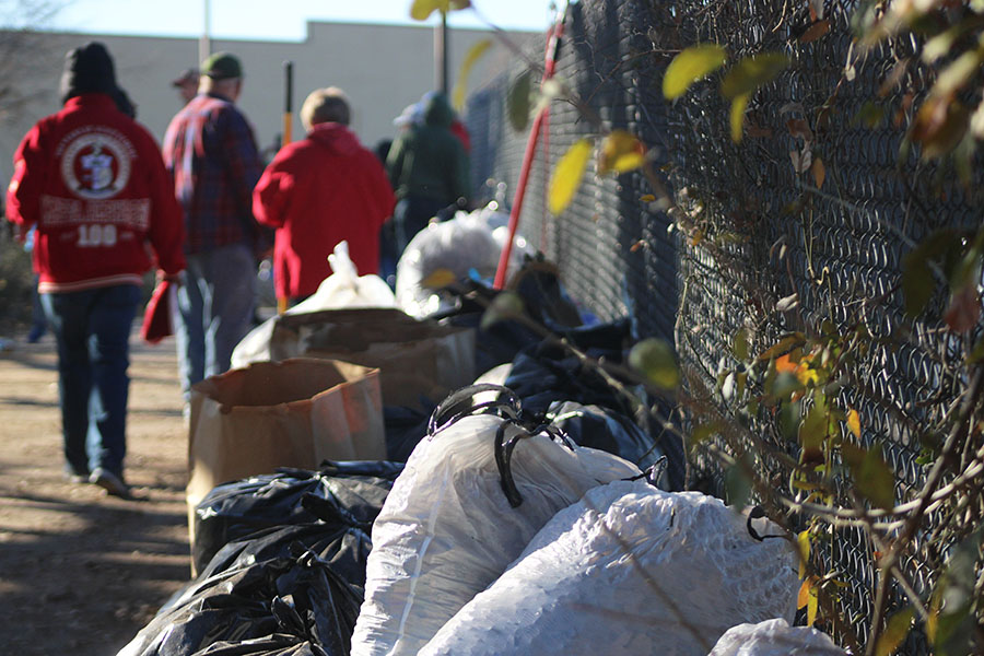 Volunteers collect a large number of trash bags filled with trash and weeds from the site.