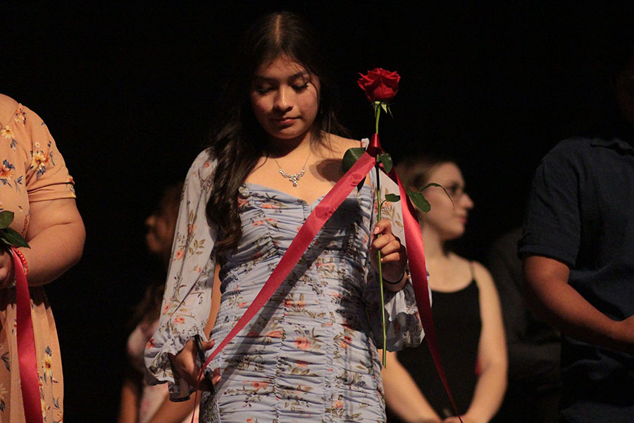 Students attached by the string around their roses walk on stage to cut the string on the right side of the rose.