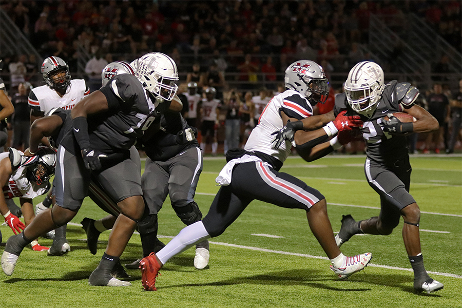 Senior Viron Ellison (21) blocks Marcus’ defensive lineman Devin Strange (17) from getting the ball. Defensive tackle Quaveon Davis (79) rushed in to defend shortly after.