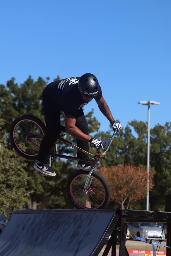 Professional BMX jumper AJ Anaya stops his bike on the front wheel while facing the crowd.