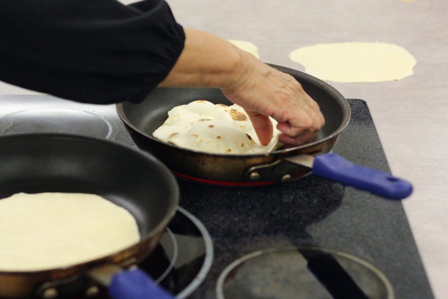 Former LISD teacher Yolanda Flores reaches into the pan to flip a tortilla. Flores taught students how to create their own dough from scratch.