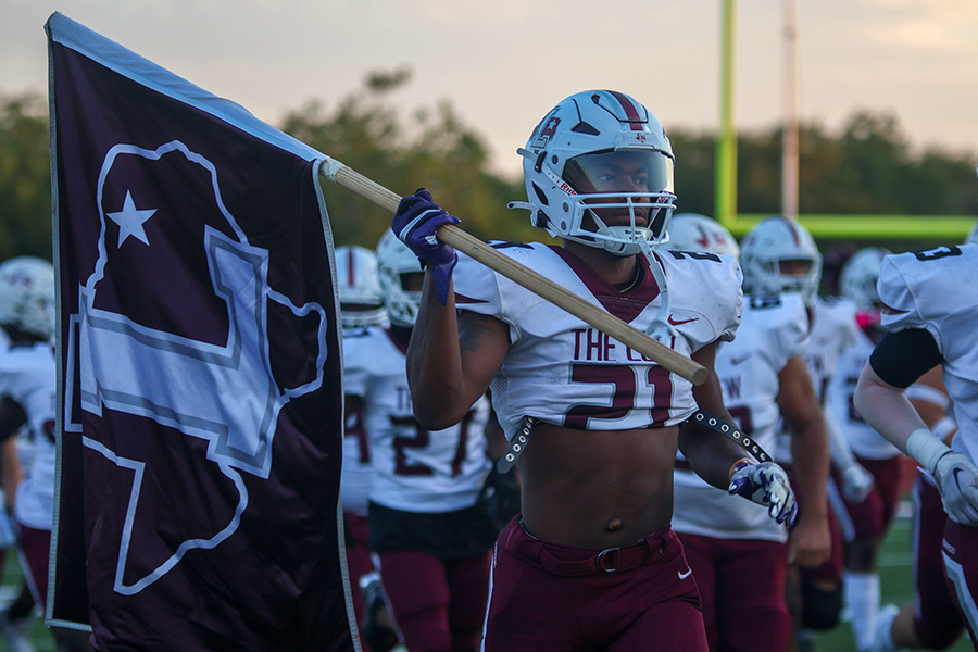 Senior running back Viron Ellison (21) leads his team onto the field while holding the school flag before the game against Mesquite. The Farmers won the game by a score of 36-0.