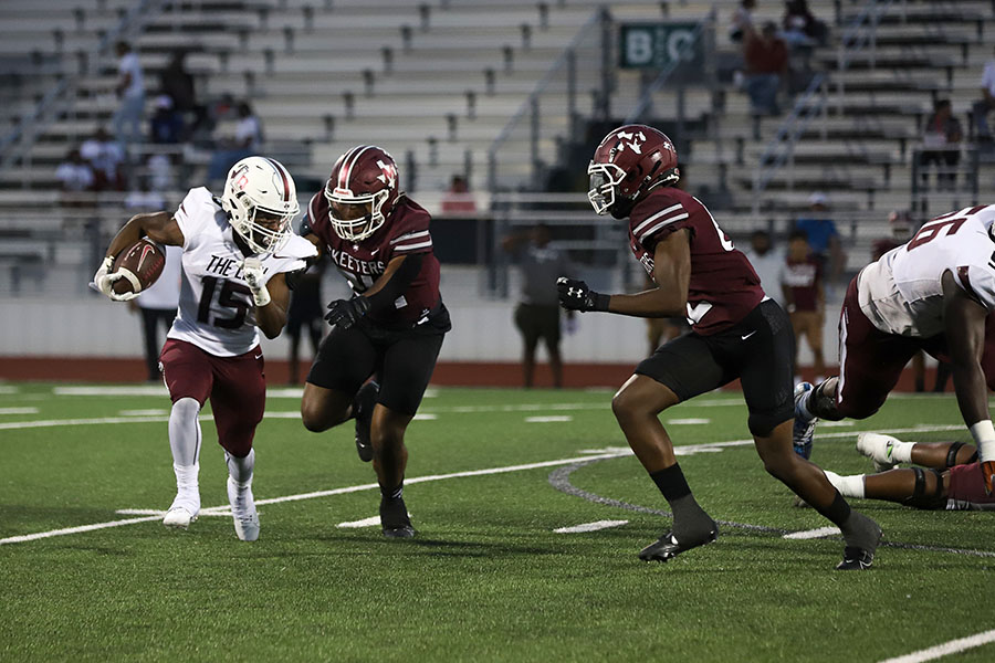 Running back Addison Wells (15) squeezes past defensive lineman Taylor Hughey in the Mesquite game on Friday, Sept. 8. The game was delayed to 7:30 p.m. because of the heat.