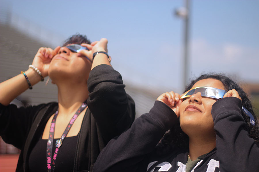Seniors Melany Perez and Lesli Cuellar spend time together to watch the eclipse.
