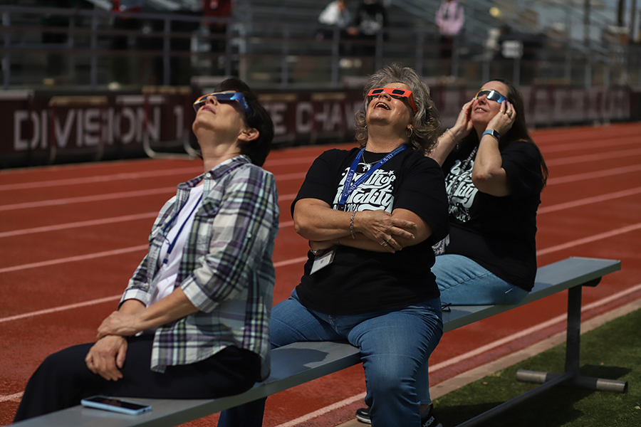 Substitute Deana Pelletier and math teachers Shari Mayes and Janice Hatter sit together to watch the eclipse in its final moments before the moons shadow completely covers the sun.