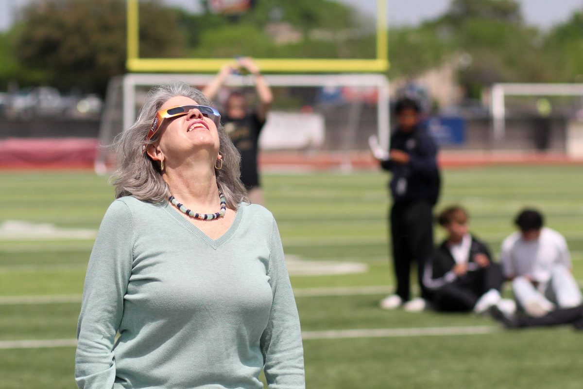 Science teacher Nancy Adams looks up at the sky to test out her eclipse glasses.