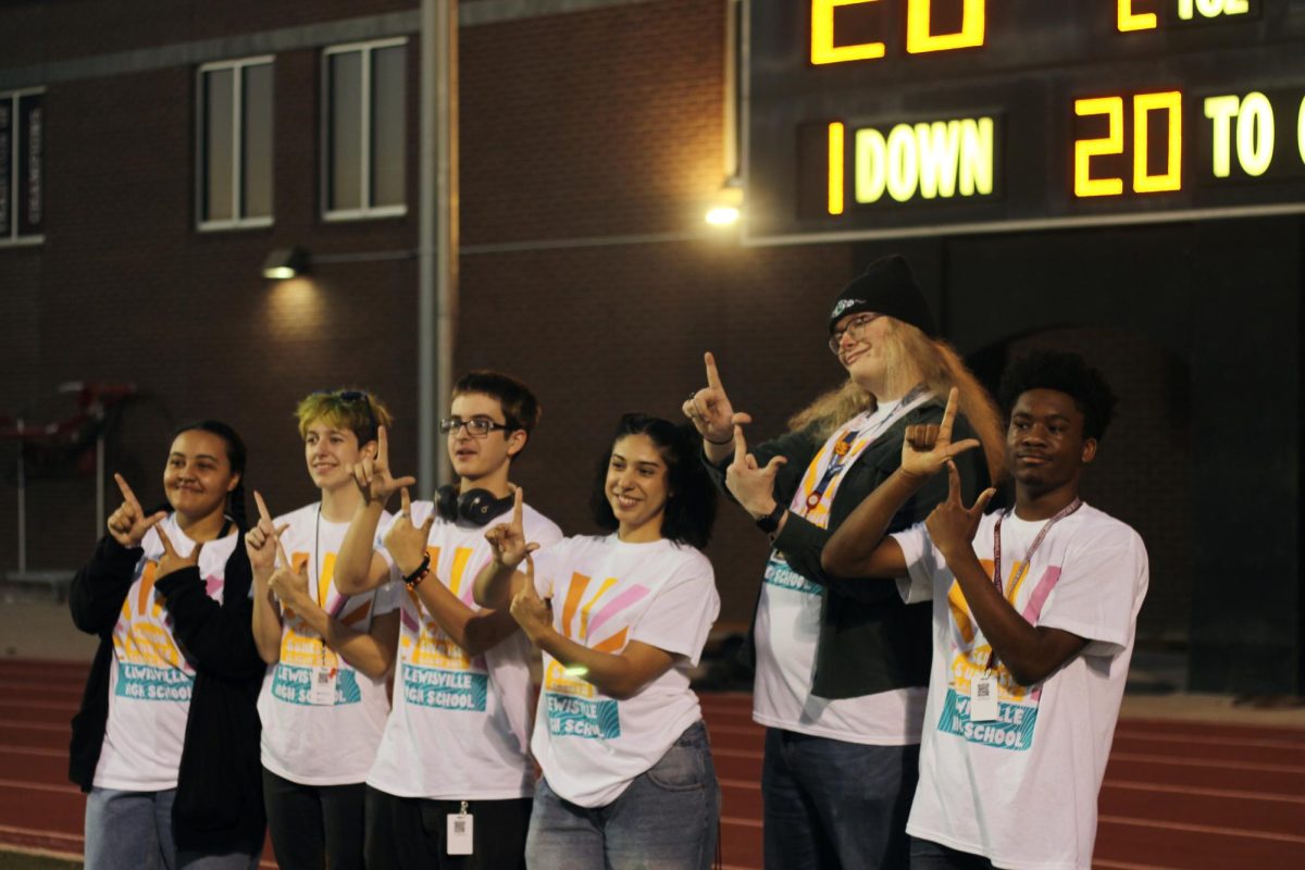 Seniors hold up the iconic Fighting Farmer ‘L’ while posing for a picture in front of the scoreboard.  