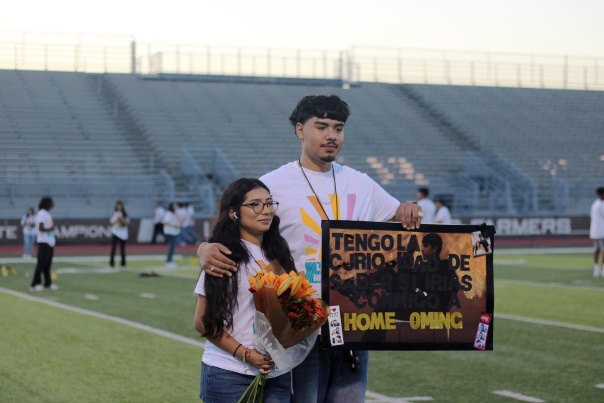 Senior Sandra Secundino and senior Alex Mandujano pose for a picture after Manujano surprised her with a Homecoming poster and a flower bouquet.