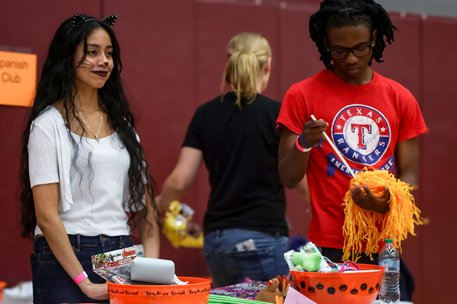 Seniors Bety Ulloa Velasquez and Riley Hamilton volunteer for the Spanish Club booth by giving candy to kids who hit the piñata. 