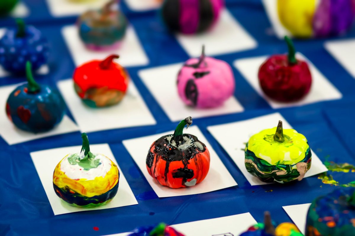 NHS booth has children painting pumpkins for their booth. 