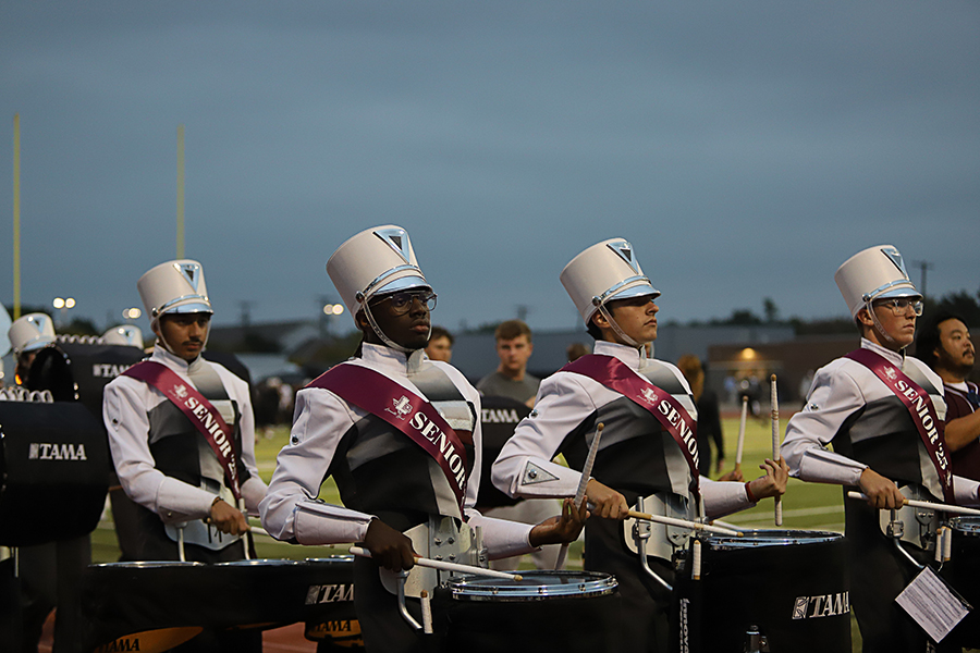 The drumline section marches during the football game. 