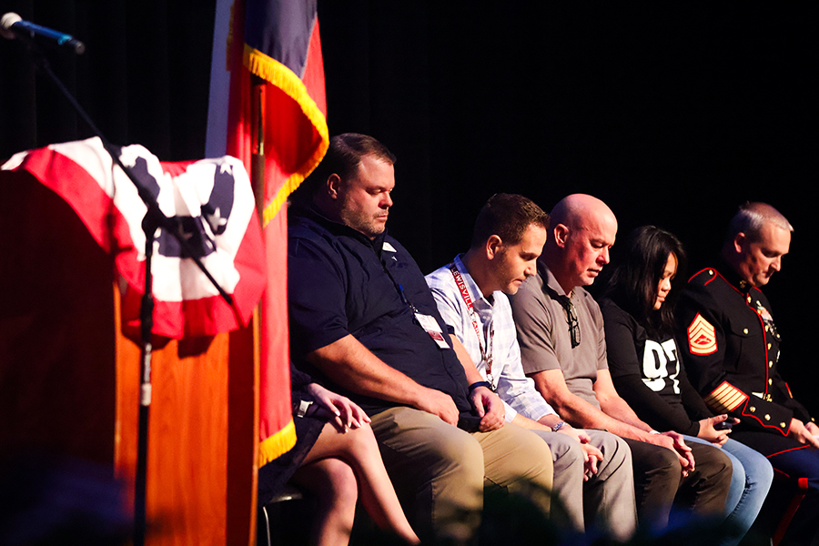 Staff members and veterans bow their heads in prayer.