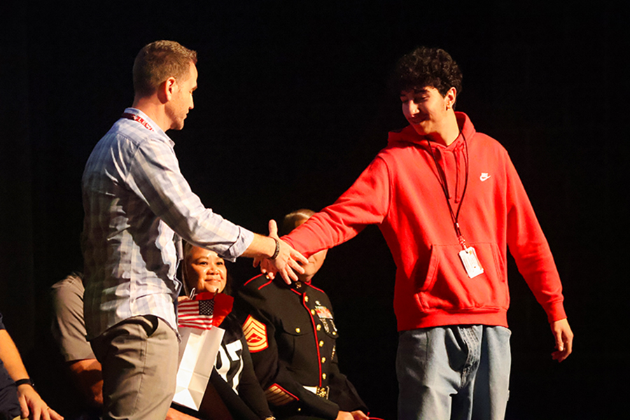 Senior community service officer Ali Harb shakes hands with history teacher Chuck Andrews to honor his service. 