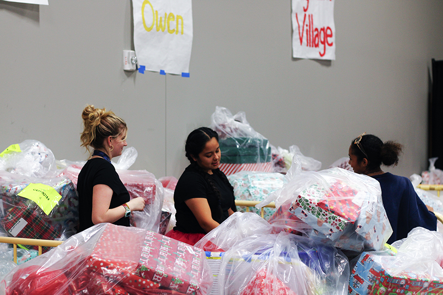 Sophomore Leah McCallum, sophomore Mia Benitez and junior Carys Williams move wrapped presents to the side.