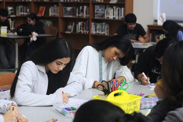 Juniors Maria Aguilar Moreno and Rachel Sung Hlei Tail create cards for soldiers as part of an Interact service event.