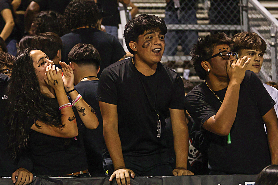 Junior Isabella Mora Barretto, senior Caneck Rodriguez and junior Maximo Valdez cheer during the football game. 